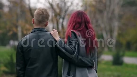 浪漫的年轻夫妇白天在秋季公园散步年轻的金发女郎穿着皮夹克拥抱视频的预览图