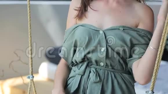 年轻漂亮的女孩穿着绿色的裙子坐在秋千上露出她温柔的身体视频的预览图