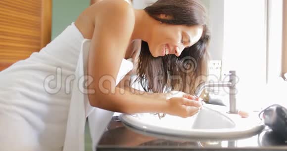 浴室里的情侣女人洗脸在毛巾里和男人聊天做晨间例行公事视频的预览图
