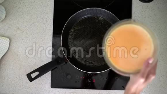 妇女将混合牛奶和鸡蛋倒入平底锅中准备早餐煎蛋卷视频的预览图