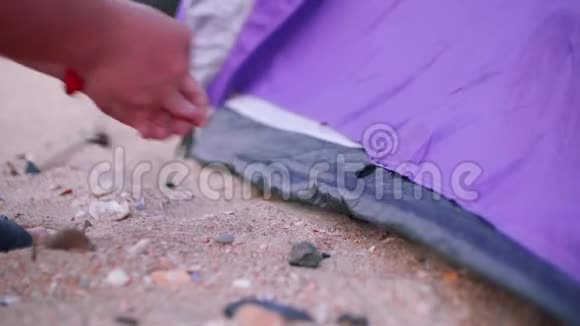 一双白色的手在海边搭起紫色的帐篷视频的预览图