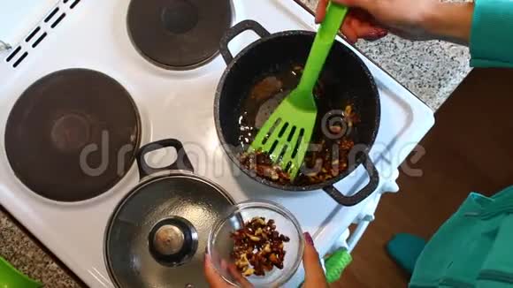一个女人正在炸碎核桃坚果放在沸腾的油里女人把它们和烹饪用的铲子混合在一起然后把它们变成一个c视频的预览图