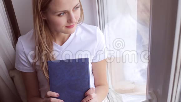 年轻女子坐在窗台上看书视频的预览图