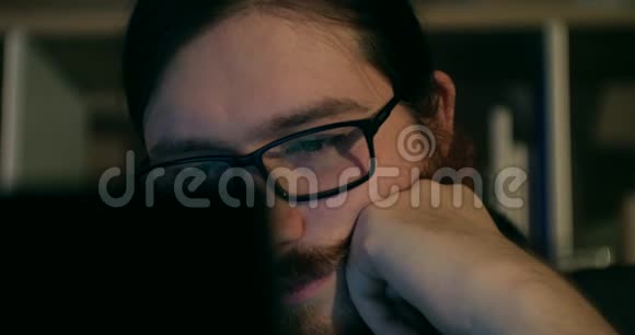 大胡子男人深夜聊天浏览特写镜头与展示眼镜反射视频的预览图