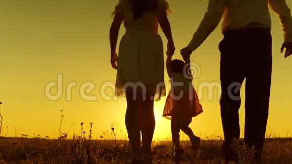爸爸和妈妈正在和小宝宝玩手握在夕阳的金色阳光下视频的预览图