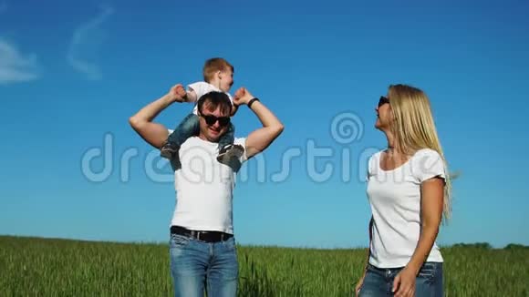 幸福的一家人在田野里奔跑和微笑他们的儿子笑着牵着手坐在鞭子上的儿子视频的预览图