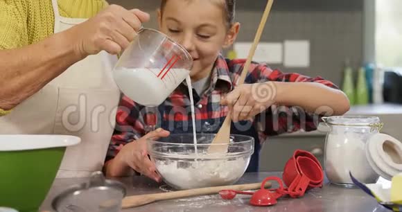 女孩混合面粉祖母倒牛奶到碗4K4K视频的预览图