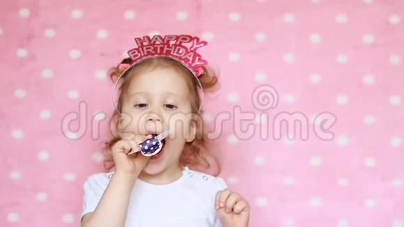 一个可爱的小女孩吹角派对微笑玩得开心笑着庆祝生日快乐恭喜你特写视频的预览图