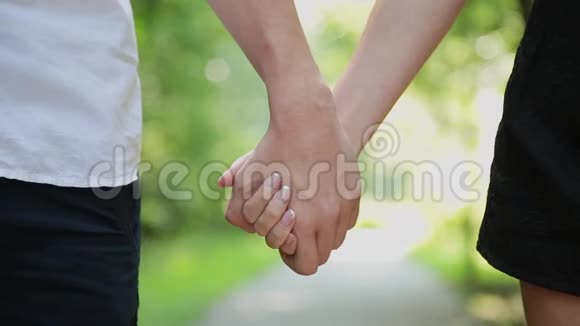 一对穿着蓝色牛仔裤的情侣携手走在一起特写视频的预览图