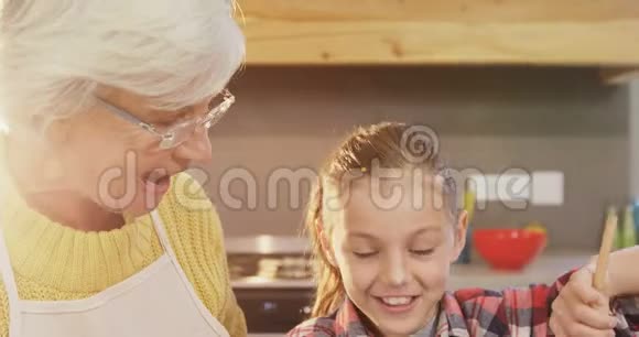 小女孩把面糊和快乐的祖母混合在一起指导她4K4K视频的预览图