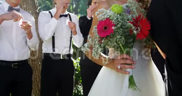 新娘和新郎在背景客人吹泡泡4K4k时接吻视频的预览图