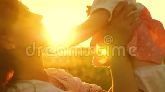 年轻美丽的母亲带着孩子在空中玩耍在金色阳光的夕阳下笑着慢动作视频的预览图