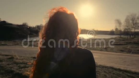年轻的红发女子站在大自然的背景下回到镜头视频的预览图