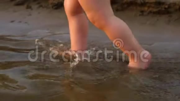 穿着尿布的小婴儿走在河岸上的第一步腿特写镜头慢动作视频的预览图