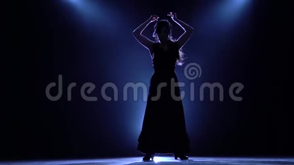 女孩在黑暗的房间里跳舞手的动作优美从后面发光烟雾背景剪影慢慢视频的预览图