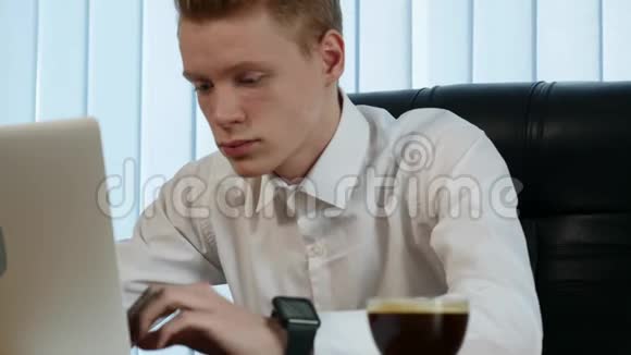 商人拿着笔记本电脑在办公桌上工作喝着咖啡周围都是大量的文件和财务视频的预览图