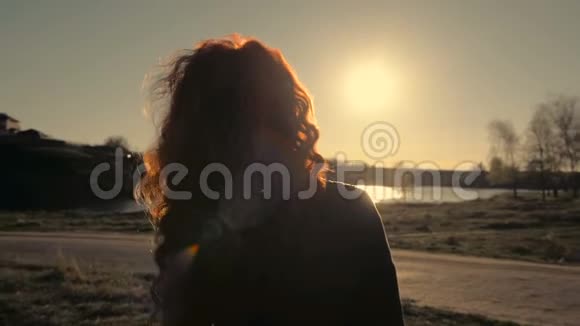年轻的红发女子站在大自然的背景下回到镜头视频的预览图