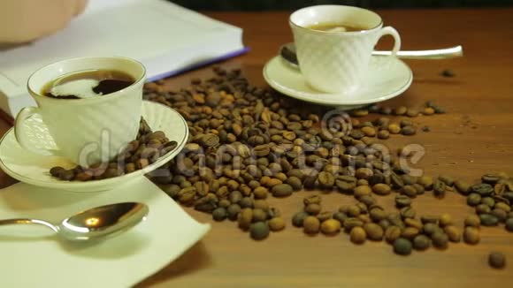 一杯浓咖啡一杯咖啡豆散落在桌子上一个女人写日记视频的预览图