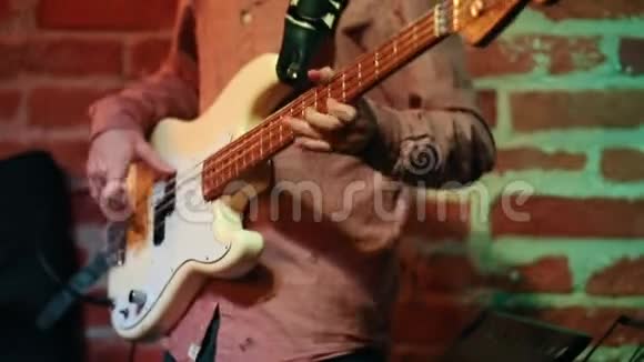 一个男人在爵士酒吧里演奏一把白色的低音吉他在架子上只有手视频的预览图