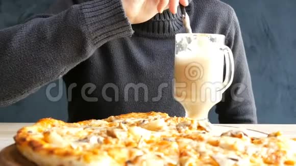 一个十几岁的男孩在一个刚出炉的夏威夷比萨饼的背景下喝着一杯吸管拿铁咖啡视频的预览图