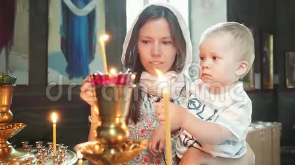 教堂里有个孩子的女孩点燃了蜡烛视频的预览图