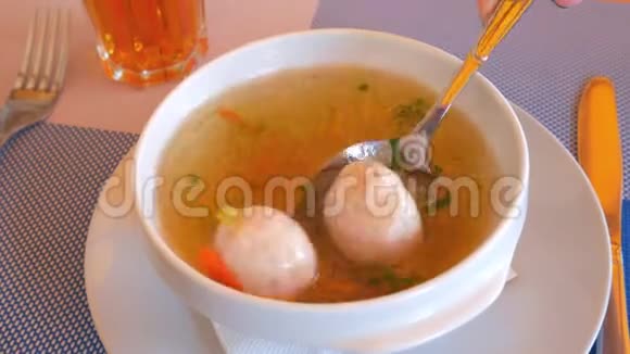 女孩勺子将防止汤与肉球和土豆在旋转的白色盘子视频的预览图