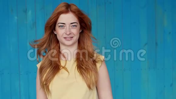 照片中的年轻红发女士站在白色墙壁背景上孤立看着相机自拍视频的预览图
