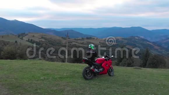一个骑摩托车的人年轻的帅哥骑摩托车在山路上他站在摩托车旁边视频的预览图