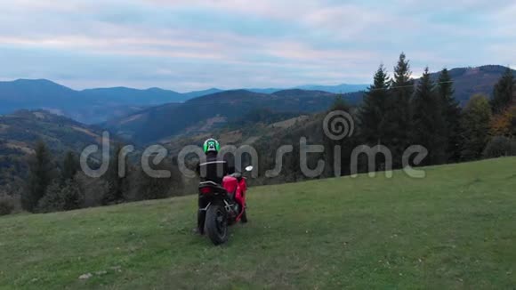 一个骑摩托车的人年轻的帅哥骑摩托车在山路上他站在摩托车旁边视频的预览图