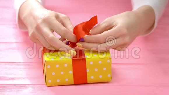 手工编织的手在礼品盒上系丝带视频的预览图