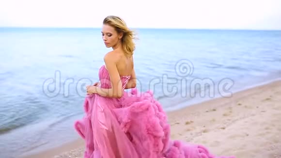 金发的年轻女子在海上穿着令人惊叹的白色粉色婚纱视频的预览图