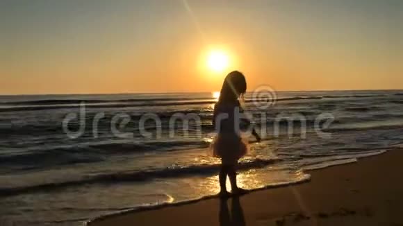 日落时小女孩在海滩上跳舞视频的预览图