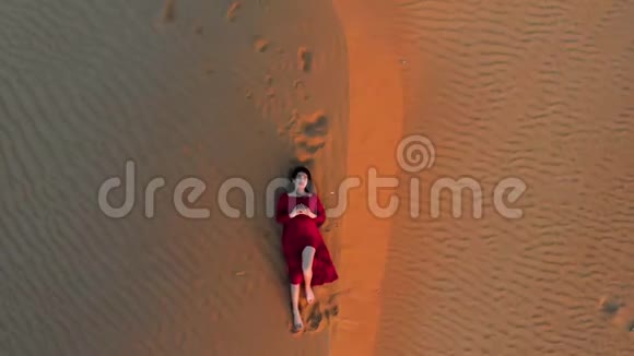 日落鸟瞰沙漠沙滩上的女人视频的预览图