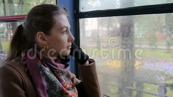 一个美丽的女孩带着悲伤的眼睛坐在电车慢动作中视频的预览图