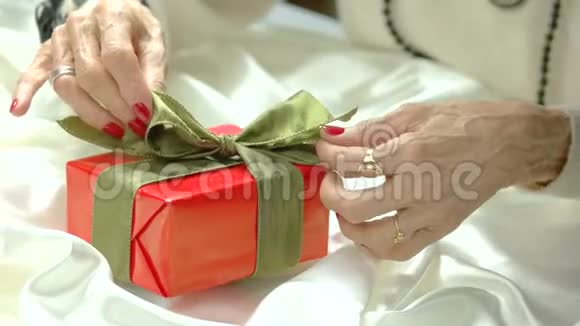 女性双手在礼盒上系红绿蝴蝶结视频的预览图