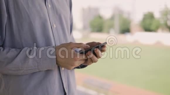 使用智能手机的人看着体育场里手机上的屏幕视频的预览图