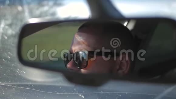 戴太阳镜的年轻人正在开车车辆后视镜内的反射面视频的预览图