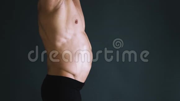 强大的健美与六包完美的腹肌显示真空锻炼的压力在黑色背景上摆姿势的男人视频的预览图