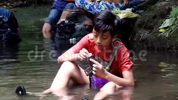 菲律宾农村社区缺乏公共供水系统的公用设施迫使这个男孩即使在污染的里也要洗澡和洗澡视频的预览图