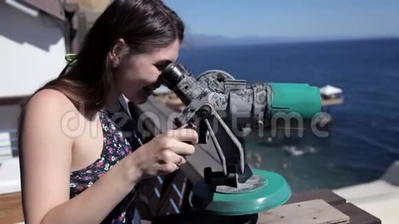 一个小女孩站在观景台上俯瞰大海用望远镜观察视频的预览图