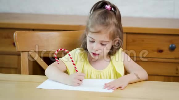 小女孩穿着黄色的连衣裙用铅笔在纸上画画视频的预览图