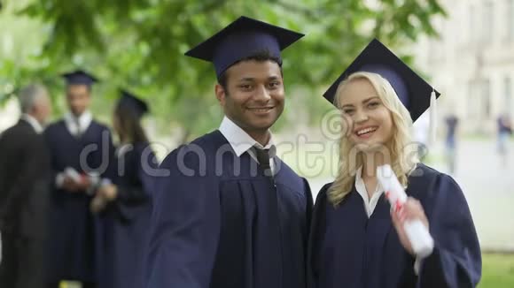 男性和女性毕业生带着毕业证书和微笑完成高中教育视频的预览图