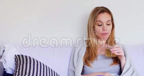 裹着毯子的女人在客厅里喝绿茶视频的预览图