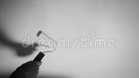 女性用滚筒将墙壁涂成白色黑白镜头接近16毫米风格视频的预览图