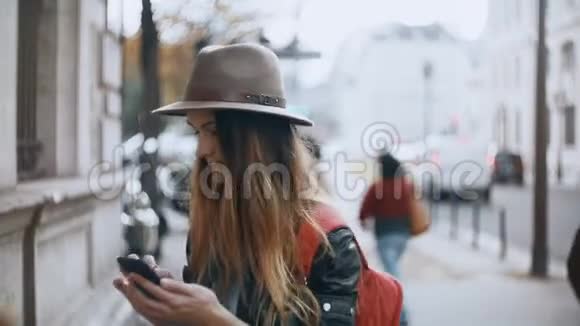 年轻漂亮的女人站在法国巴黎的街上用智能手机浏览互联网视频的预览图