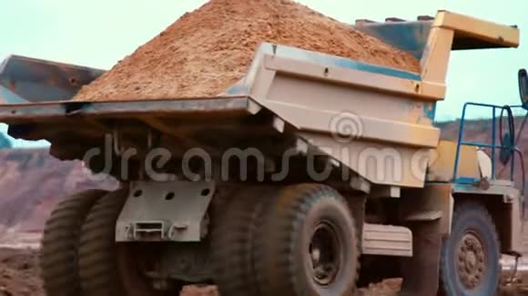 肮脏的卡车在采石场的道路上运输沙子大型黄色翻斗车视频的预览图