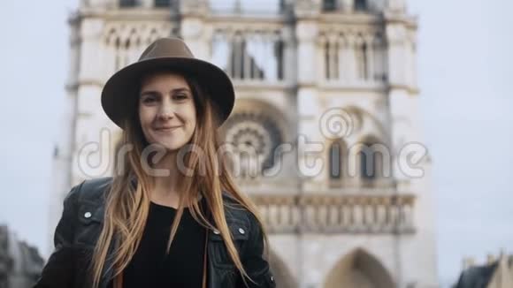 法国巴黎圣母大教堂附近戴着帽子的年轻美女的肖像看着镜头视频的预览图
