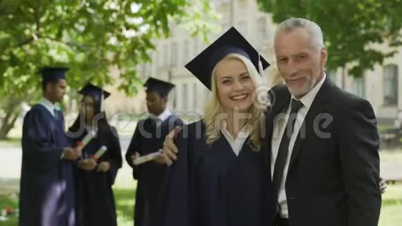 女毕业生拥抱爸爸微笑着进入镜头成功的未来事业视频的预览图