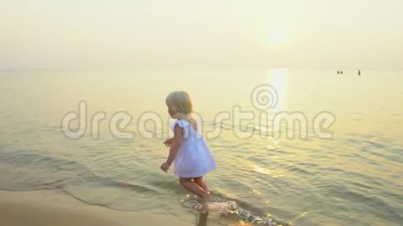 小女孩可爱的女孩在美丽的日落沙滩上奔跑在慢动作中度过快乐的假期孩子有视频的预览图