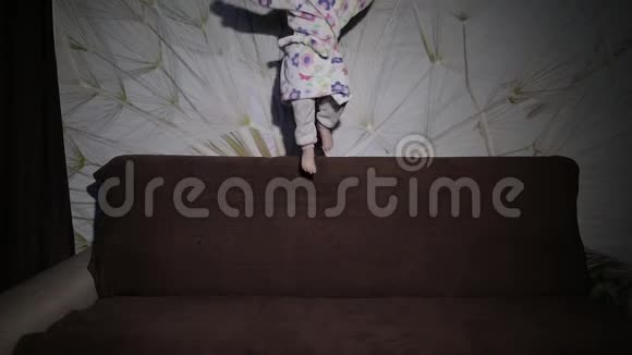 金发可爱的小女孩跳上沙发浴衣快乐视频的预览图